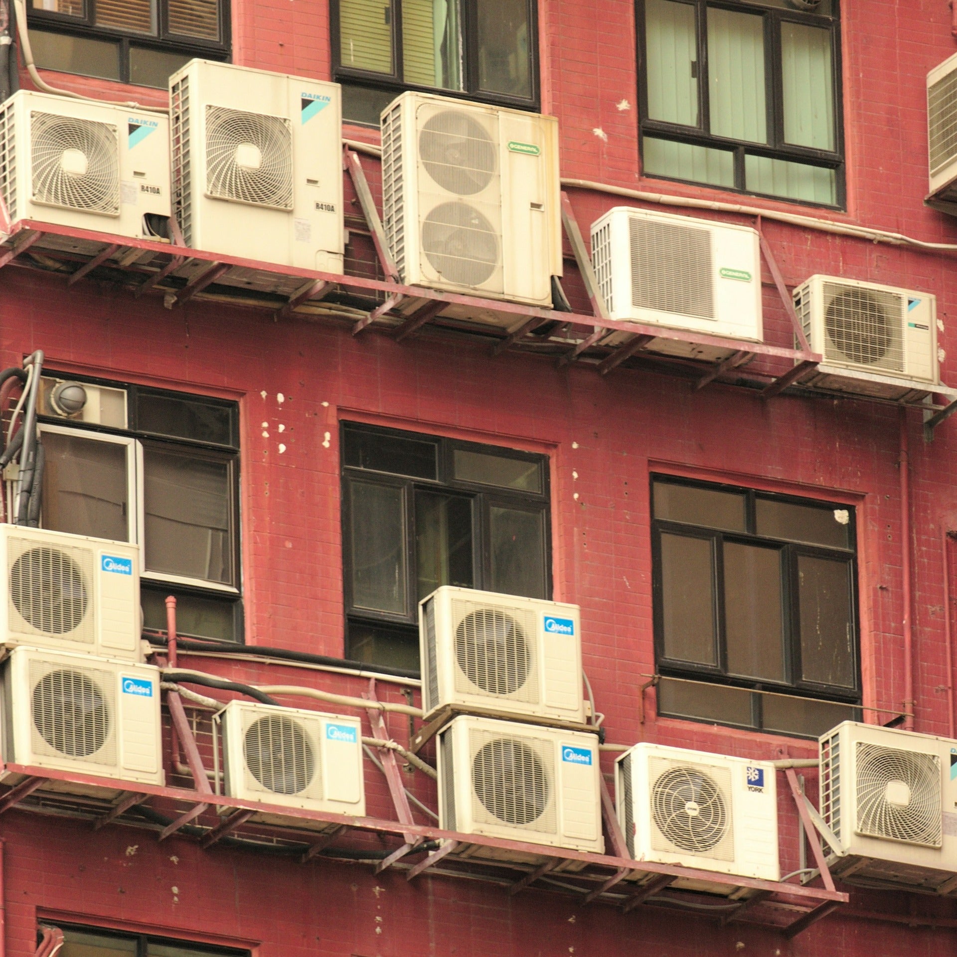 Multiple building cooling fan systems on the outside of a red building